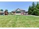 Expansive backyard featuring a patio, play structure, lush lawn, and mature trees at 7413 Misty Woods Ln, Indianapolis, IN 46237