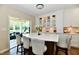 Bright kitchen featuring white cabinets, quartz countertops and an island with seating overlooking the sunroom at 7413 Misty Woods Ln, Indianapolis, IN 46237