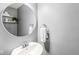 Cozy bathroom features a round mirror, modern fixtures, floating shelf, and a neutral gray color scheme at 7616 E Concord Ln, Fishers, IN 46038