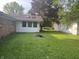 Green backyard featuring trees and home exterior with skylights at 7721 Hollybrook Ln, Indianapolis, IN 46227