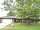 Charming brick home with an attached garage, tidy front yard, and a beautiful shade tree at 7721 Hollybrook Ln, Indianapolis, IN 46227