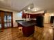 View of open concept kitchen with cherry cabinets, island cooktop, and hardwood floors at 7721 Hollybrook Ln, Indianapolis, IN 46227