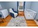 Cute Bedroom with hardwood floors, a white crib, blue glider, and playful decor at 828 N Butler Ave, Indianapolis, IN 46219