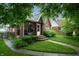 Charming brick home featuring a beautifully landscaped front yard with a welcoming porch and walkway at 828 N Butler Ave, Indianapolis, IN 46219