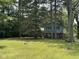 Two-story home with light-blue siding with red brick foundation surrounded by mature trees and a green lawn at 9011 Camby Rd, Camby, IN 46113