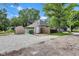 Backyard showcasing a gravel drive, a storage shed, and a small deck, surrounded by mature trees and green grass at 917 W Pearl St, Lebanon, IN 46052