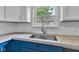 A close-up of the kitchen sink and subway tile backsplash with blue lower cabinets and a view from the window at 917 W Pearl St, Lebanon, IN 46052