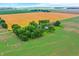 Wide aerial view showcases a lovely property with a farmhouse, surrounded by vibrant green and golden fields at 9237 N 500 W, Fountaintown, IN 46130