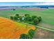 Scenic aerial shot of a charming farmhouse nestled amongst trees, bordering golden and green fields at 9237 N 500 W, Fountaintown, IN 46130