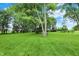 Expansive backyard with lush green grass and mature trees under a bright blue sky with scattered clouds at 9237 N 500 W, Fountaintown, IN 46130