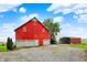 Vibrant red barn with multiple garage doors, complemented by gravel driveway and verdant surroundings at 9237 N 500 W, Fountaintown, IN 46130