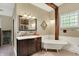 Charming bathroom featuring a clawfoot tub, vanity with sink, decorative fixtures, and natural lighting through a window at 9237 N 500 W, Fountaintown, IN 46130