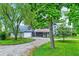 Gray home with detached garage and screened porch, showcasing a gravel driveway and mature landscaping at 9237 N 500 W, Fountaintown, IN 46130