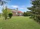 Large backyard featuring a well-maintained lawn, mature trees, and patio with a grill at 9302 N Bayland Dr, McCordsville, IN 46055