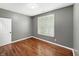 Bedroom featuring hardwood floors, neutral walls, bright windows with shutters, and a white door at 9302 N Bayland Dr, McCordsville, IN 46055