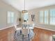 Well-lit dining area with a glass table, white chairs, plantation shutters and modern lighting at 9302 N Bayland Dr, McCordsville, IN 46055