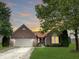 Charming single-story brick home with a well-manicured lawn, mature trees, and an attached two-car garage at 9302 N Bayland Dr, McCordsville, IN 46055