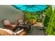 A serene patio with wicker chairs, a dark brown table, and lush greenery, all shaded by a blue umbrella at 9520 Settlement W Dr, Indianapolis, IN 46250