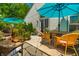 A cozy patio with wicker furniture, colorful potted plants, and a table shaded by a bright blue umbrella at 9520 Settlement W Dr, Indianapolis, IN 46250