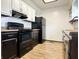 Well-lit kitchen with black appliances, dark cabinets, and wood floors at 100 Justin Dr, Mooresville, IN 46158