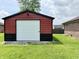 Red and black outbuilding with white garage door sits on a green lawn next to a brick building at 100 Justin Dr, Mooresville, IN 46158