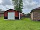 Red and black outbuilding with white door, garage door, and green lawn at 100 Justin Dr, Mooresville, IN 46158