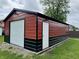 View of the red and black outbuilding, featuring a garage door and white door with lights above at 100 Justin Dr, Mooresville, IN 46158