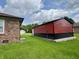 View of red and black outbuilding with white door, located on a well-maintained lawn at 100 Justin Dr, Mooresville, IN 46158