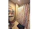 Cozy bathroom featuring a patterned shower curtain, toilet with wooden seat, and shelving for linens at 1027 Springway Dr, Shelbyville, IN 46176