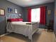 Bedroom with gray walls, white metal bedframe with red linens, window with red curtains and carpeted floor at 1027 Springway Dr, Shelbyville, IN 46176