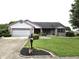 Charming single-story brick home featuring a well-manicured lawn and attached two-car garage at 1027 Springway Dr, Shelbyville, IN 46176