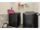A modern laundry room featuring black washer and dryer sets, and an ironing board at 10811 Wild Orchard Ln, Indianapolis, IN 46239