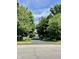 Property entrance featuring black asphalt driveway, iron gate, landscaping, and lush trees at 11557 Willow Springs Dr, Zionsville, IN 46077