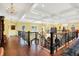 Hallway featuring dark hardwood floors, ornate railings, and decorative chandeliers illuminating the space at 11557 Willow Springs Dr, Zionsville, IN 46077