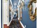 Hallway with blue walls and intricate carpet, illuminated by chandeliers at 11557 Willow Springs Dr, Zionsville, IN 46077