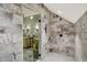 Contemporary shower featuring sleek glass enclosure, neutral stone tiling, and built-in shelving for organization at 11557 Willow Springs Dr, Zionsville, IN 46077