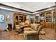 A cozy sitting area features hardwood floors and blue-gray walls with a curio cabinet and accent furniture at 11557 Willow Springs Dr, Zionsville, IN 46077