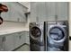 A modern laundry room with gray cabinets, white countertops, and a front-loading washer and dryer at 12839 Bird Cage, Carmel, IN 46032