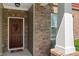 Close-up of a welcoming front door with brick accents, decorative wreath, and a patriotic welcome mat at 13992 Wynngate Ln, Fishers, IN 46038