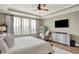 Relaxing bedroom featuring tray ceilings, a ceiling fan, a comfortable chair and a large window at 14682 Braemar E Ave, Noblesville, IN 46062