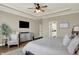 Relaxing main bedroom featuring tray ceilings, a ceiling fan, a doorway to a bathroom and wood flooring at 14682 Braemar E Ave, Noblesville, IN 46062