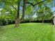 Expansive green backyard featuring mature trees, offering a serene outdoor space for relaxation and recreation at 228 W Washington St, Shelbyville, IN 46176
