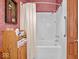 This bathroom features a tiled shower, along with vintage-patterned wallpaper, and a wooden storage cabinet at 228 W Washington St, Shelbyville, IN 46176