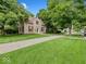 Inviting two-story home with charming red shutters surrounded by a lush green lawn and mature trees at 228 W Washington St, Shelbyville, IN 46176