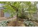 Landscaped backyard featuring a stone walkway, lush plants, and a partially-visible blue home exterior at 23 S Downey Ave, Indianapolis, IN 46219