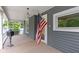 Covered front porch with an American flag and view of the landscaped yard and street at 23 S Downey Ave, Indianapolis, IN 46219