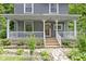 Charming front porch of a two-story home with decorative columns and a beautifully landscaped front yard at 23 S Downey Ave, Indianapolis, IN 46219