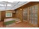 Bright sunroom with wood paneling, tile flooring and a glass roof provides natural light and a peaceful space at 23 S Downey Ave, Indianapolis, IN 46219