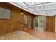 Light filled sunroom with wood paneling and tile flooring; glass door leads to the backyard at 23 S Downey Ave, Indianapolis, IN 46219