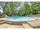 An above-ground pool surrounded by wooden decking and mature trees, perfect for summer fun at 272 N Peterman Rd, Greenwood, IN 46142